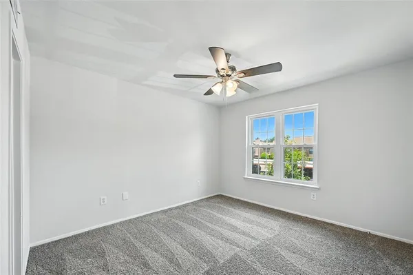 an empty room with a window and a fan