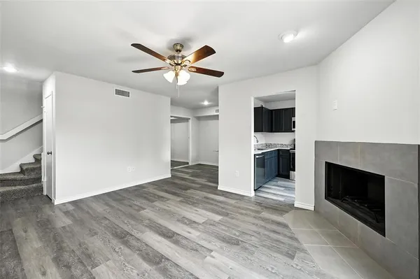 a view of a livingroom with a fireplace a ceiling fan and wooden floor