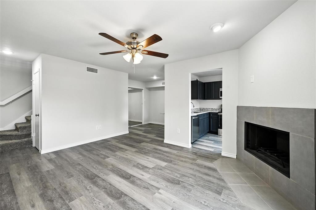 5626 Preston Oaks Road, Unit 22C Dallas, TX 75254 - Photo 9 of 29 a view of a livingroom with a fireplace a ceiling fan and wooden floor