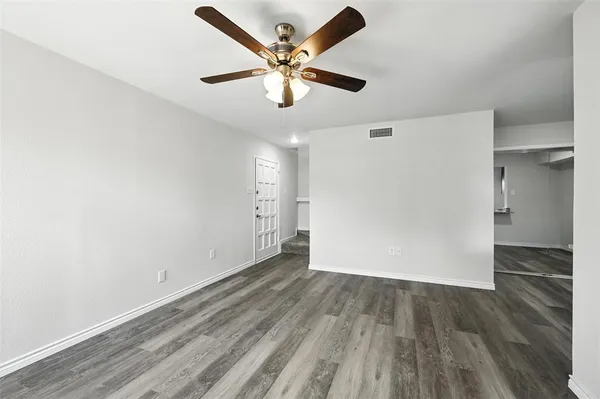 an empty room with wooden floor ceiling fan and windows