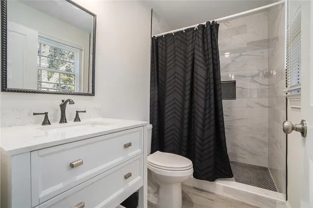 a bathroom with a granite countertop sink toilet and shower