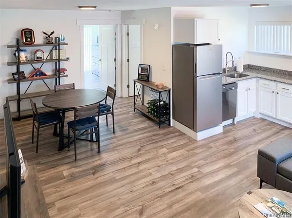 a kitchen with stainless steel appliances granite countertop a refrigerator a stove a sink dishwasher and a dining table with wooden floor