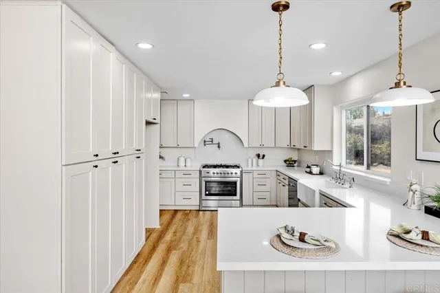 a kitchen with white cabinets a stove a sink and a window