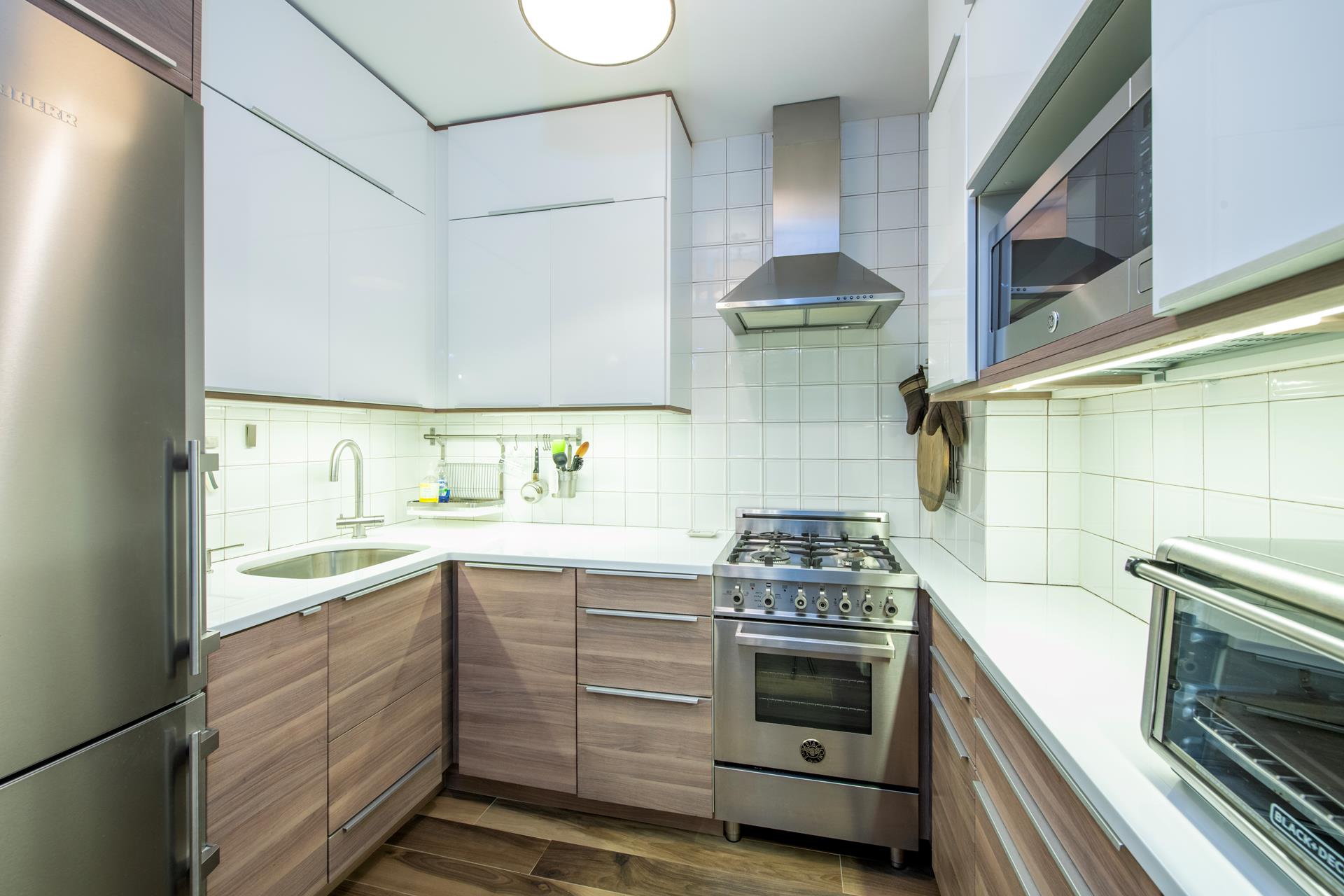 370 East 76th Street, Unit C1003 Manhattan, NY 10021 - Photo 7 of 9 a kitchen with a stove sink and cabinets
