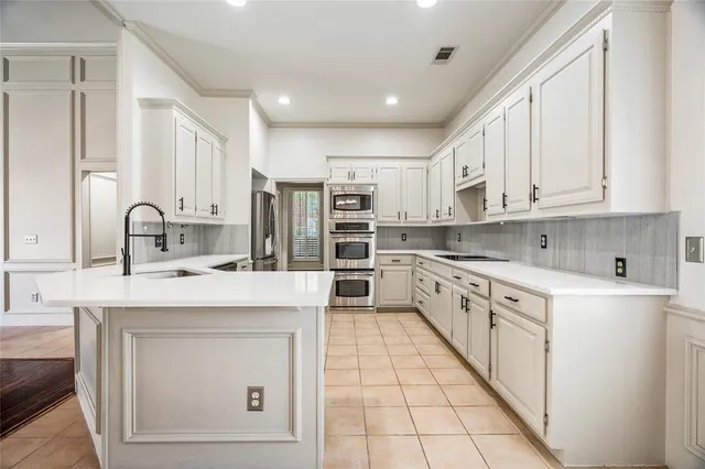 a kitchen with a sink dishwasher and white cabinets with wooden floor
