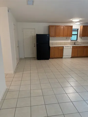 a kitchen with granite countertop a refrigerator and a stove top oven