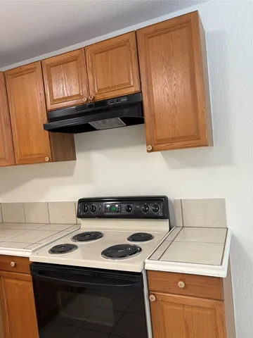 a kitchen with granite countertop wood cabinets and a stove top oven
