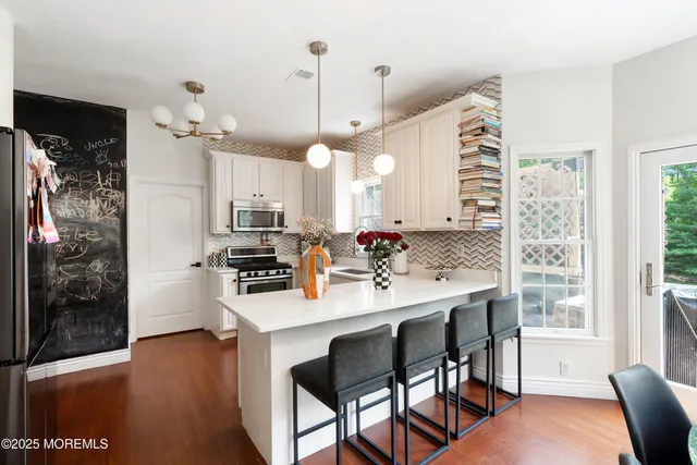 a kitchen with kitchen island a dining table chairs and a wooden floor