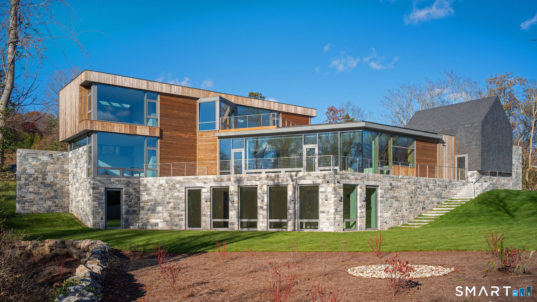 314 Ferry Road Old Lyme, CT 06371 - Photo 31 of 40 The exterior of Greystone is as impressive as the inside. With a nod to an old barn foundation that was on the property, the architect used granite for the facade, accented with slate tiles and Kebony wood cladding.