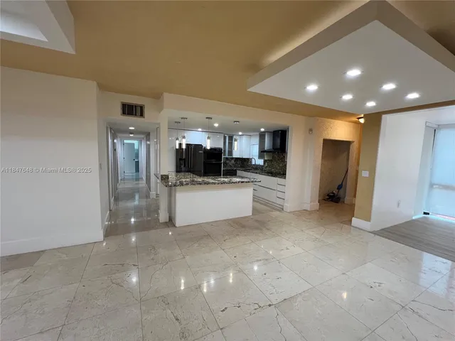 a view of a kitchen with refrigerator and white cabinets