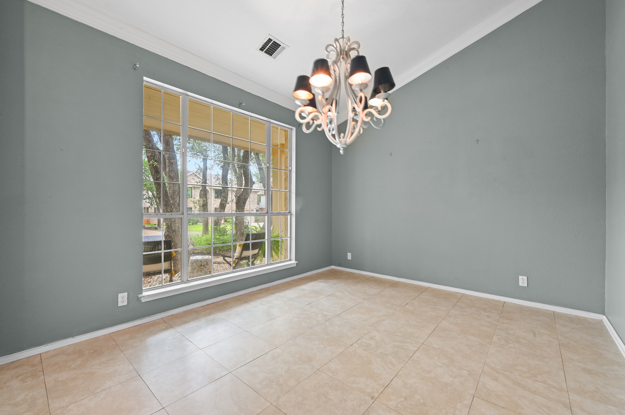 5313 Moon Shadow Drive Austin, TX 78735 - Photo 9 of 30 Spacious room featuring a contemporary chandelier, large picture window with grid detailing, crown molding, tile flooring, and painted walls