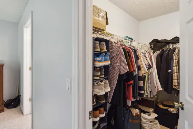 a view of walk in closet with clothes and shoes