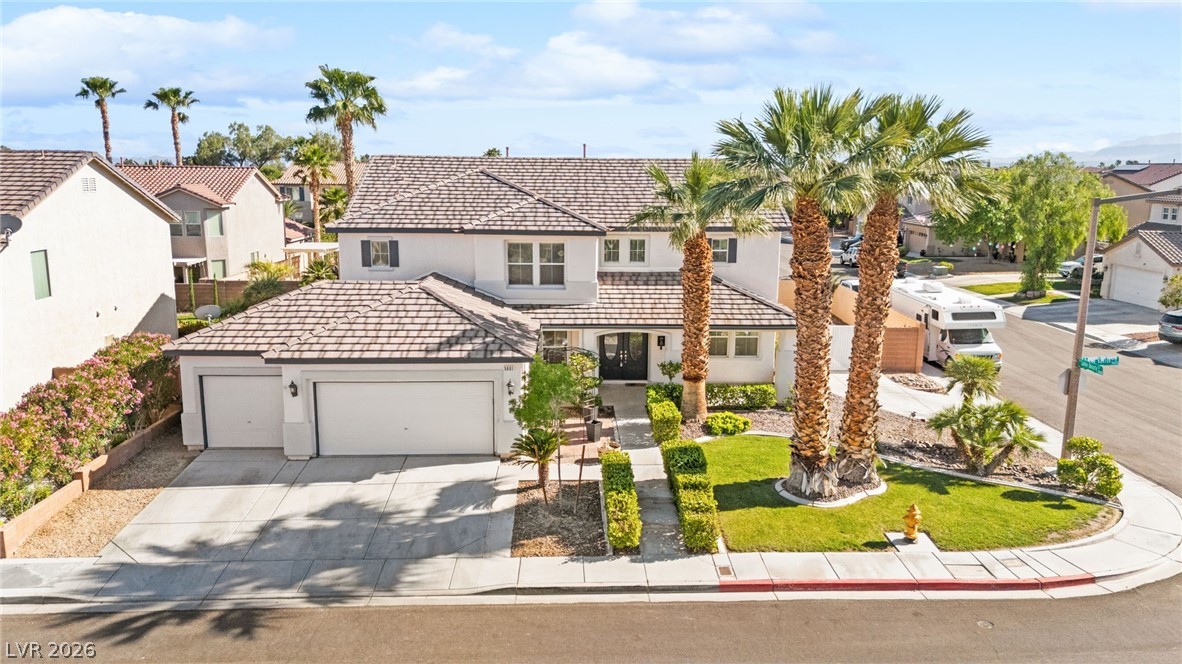 View of front of house with an attached garage, a residential view, driveway, stucco siding, and a tile roof