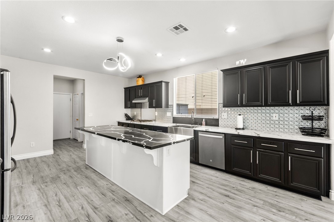 5601 Rocky Ravine Avenue Las Vegas, NV 89131 - Photo 19 of 71 Kitchen with a center island, dark cabinets, dark stone counters, stainless steel appliances, and a kitchen bar