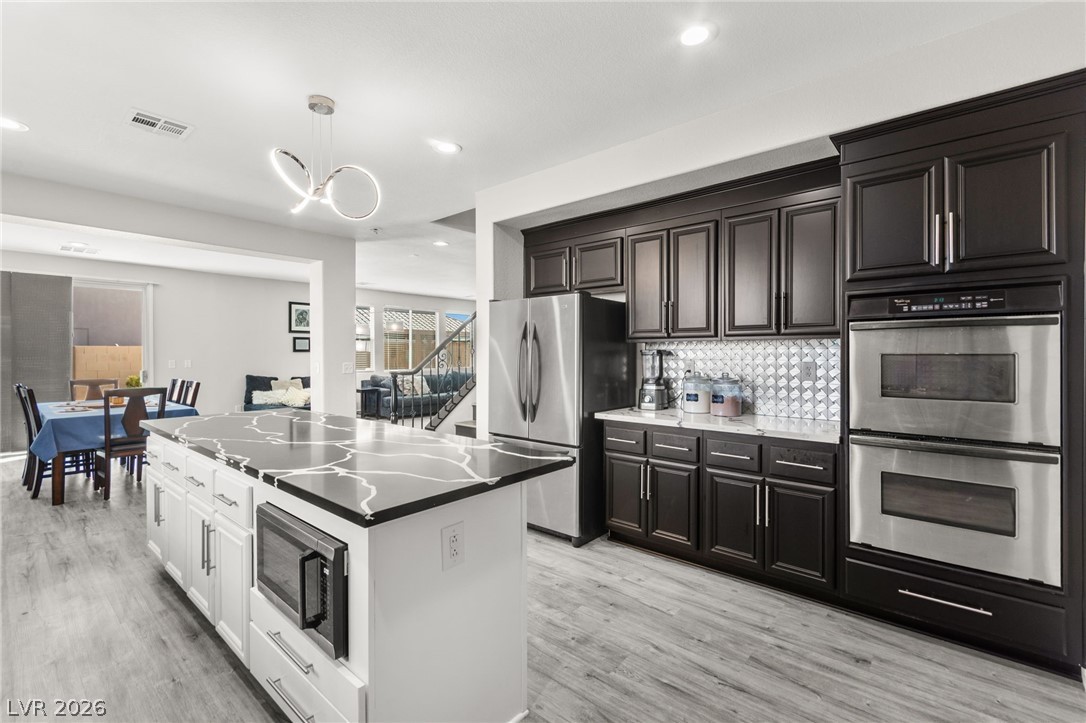 5601 Rocky Ravine Avenue Las Vegas, NV 89131 - Photo 23 of 71 Kitchen with stainless steel appliances, light wood-style floors, a kitchen island, and tasteful backsplash