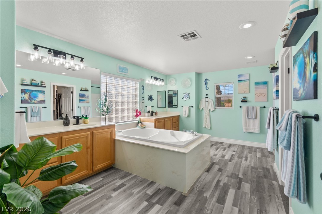 5601 Rocky Ravine Avenue Las Vegas, NV 89131 - Photo 44 of 71 Bathroom with vanity, light wood-style flooring, a bath, recessed lighting, and a textured ceiling