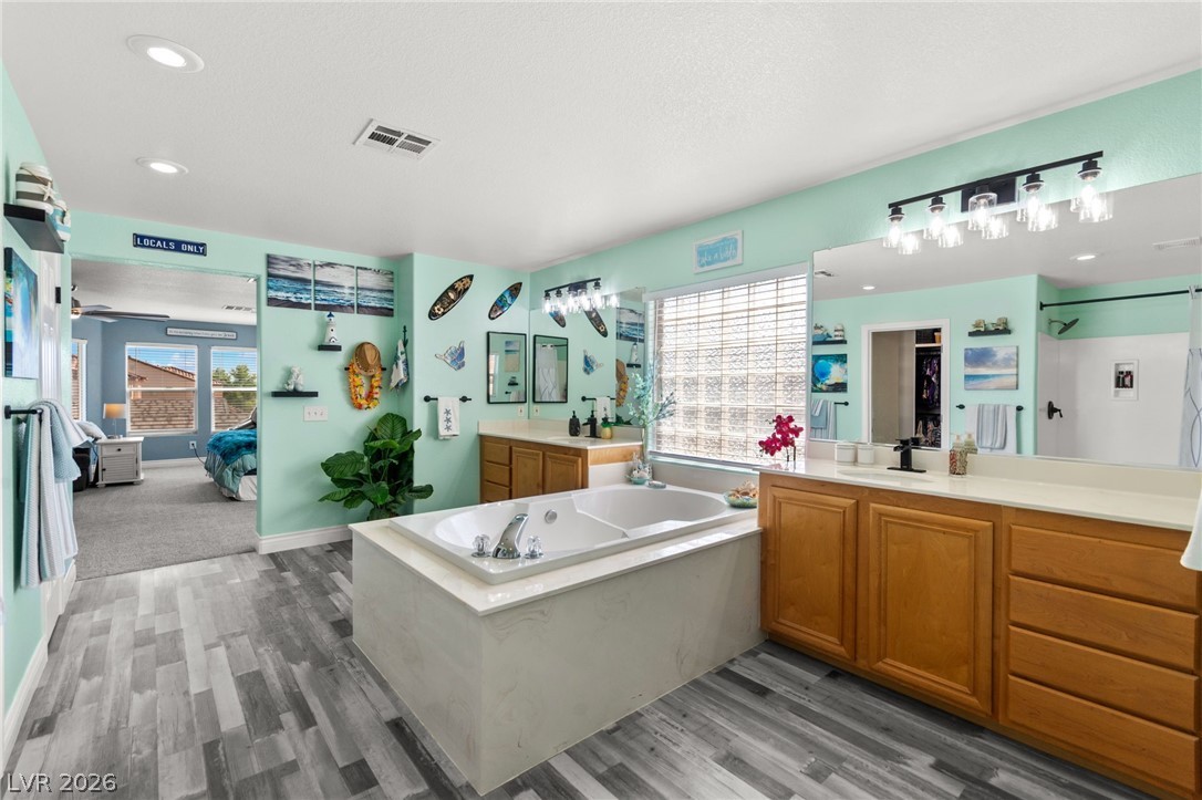 5601 Rocky Ravine Avenue Las Vegas, NV 89131 - Photo 46 of 71 Ensuite bathroom with two vanities, light wood-style floors, a bath, and recessed lighting