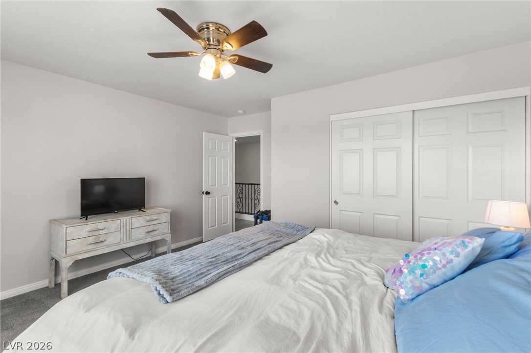 5601 Rocky Ravine Avenue Las Vegas, NV 89131 - Photo 55 of 71 Bedroom featuring a ceiling fan, dark carpet, and a closet