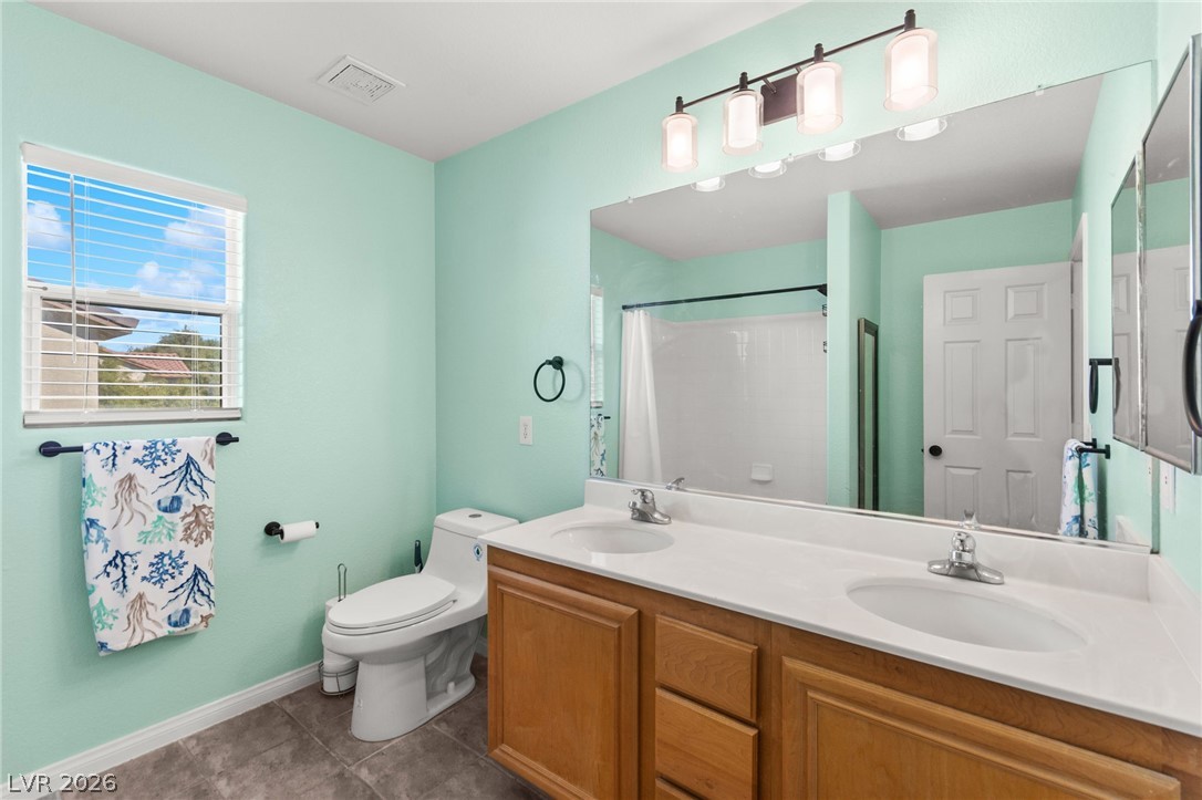 5601 Rocky Ravine Avenue Las Vegas, NV 89131 - Photo 59 of 71 Full bathroom featuring double vanity, dark tile patterned floors, and a shower with curtain
