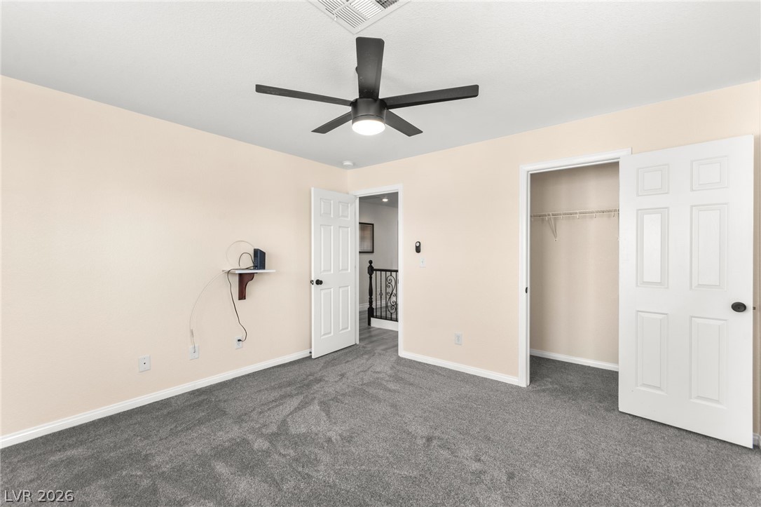 5601 Rocky Ravine Avenue Las Vegas, NV 89131 - Photo 62 of 71 Unfurnished bedroom with dark carpet, a closet, and a ceiling fan