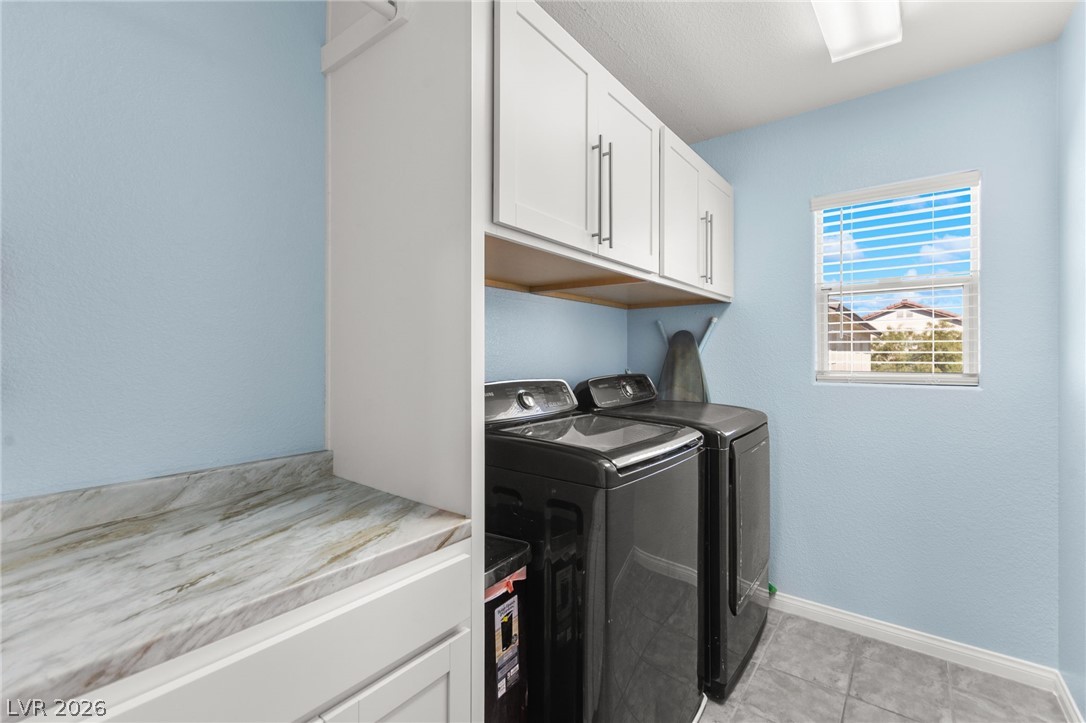 5601 Rocky Ravine Avenue Las Vegas, NV 89131 - Photo 63 of 71 Laundry room with cabinet space, independent washer and dryer, light tile patterned floors, and a textured wall