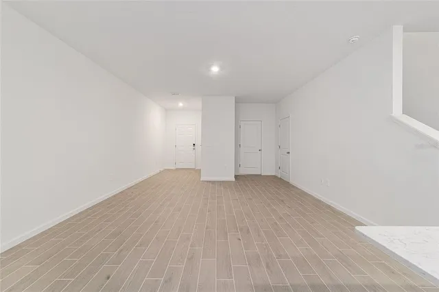 a view of kitchen and empty room with wooden floor