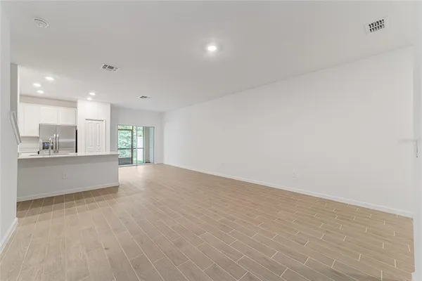 a large white kitchen with stainless steel appliances granite countertop a stove a sink and a refrigerator with wooden floor