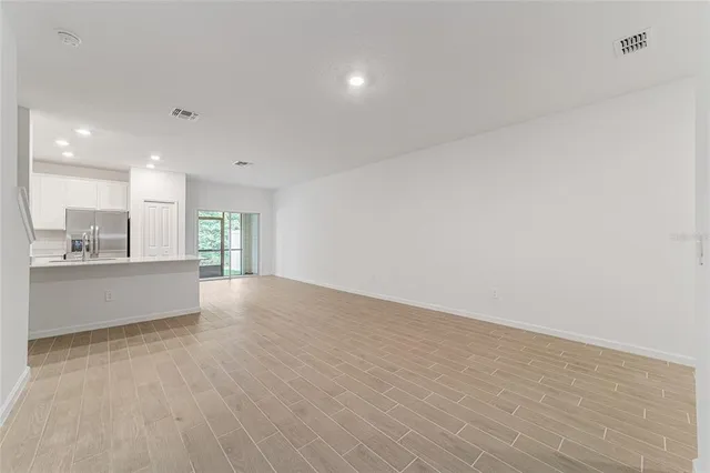 a large white kitchen with stainless steel appliances granite countertop a stove a sink and a refrigerator with wooden floor