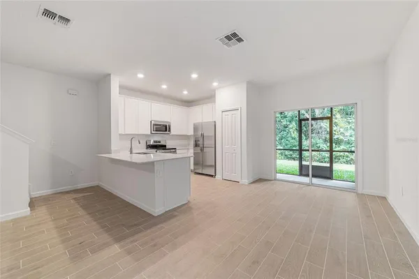 a large white kitchen with kitchen island a sink stainless steel appliances and white cabinets