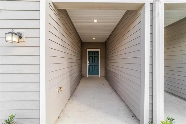 a view of a hallway with wooden floor and a kitchen