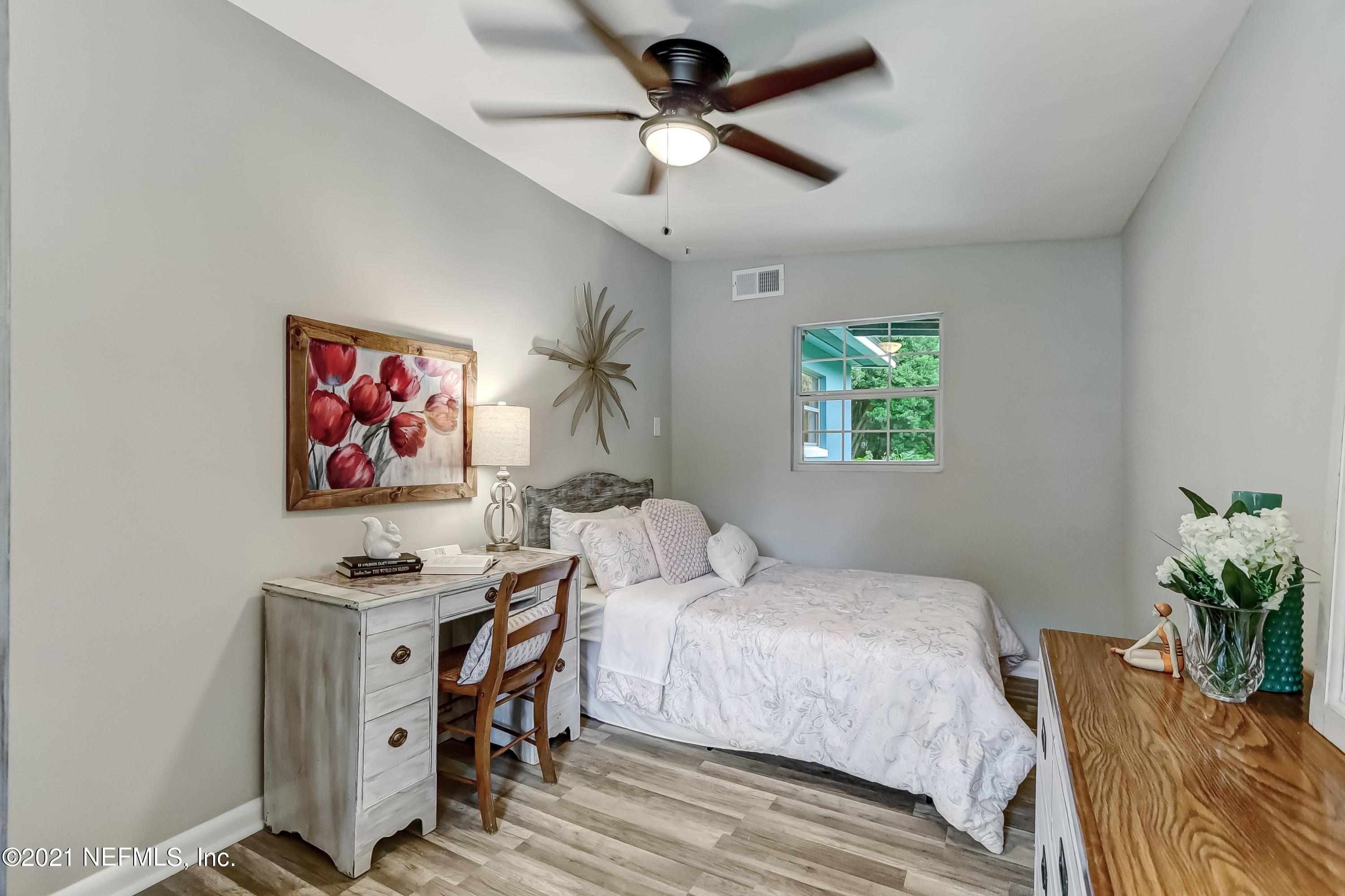6914 Rollo Road Jacksonville, FL 32205 - Photo 16 of 31 a bedroom with a bed and a chandelier