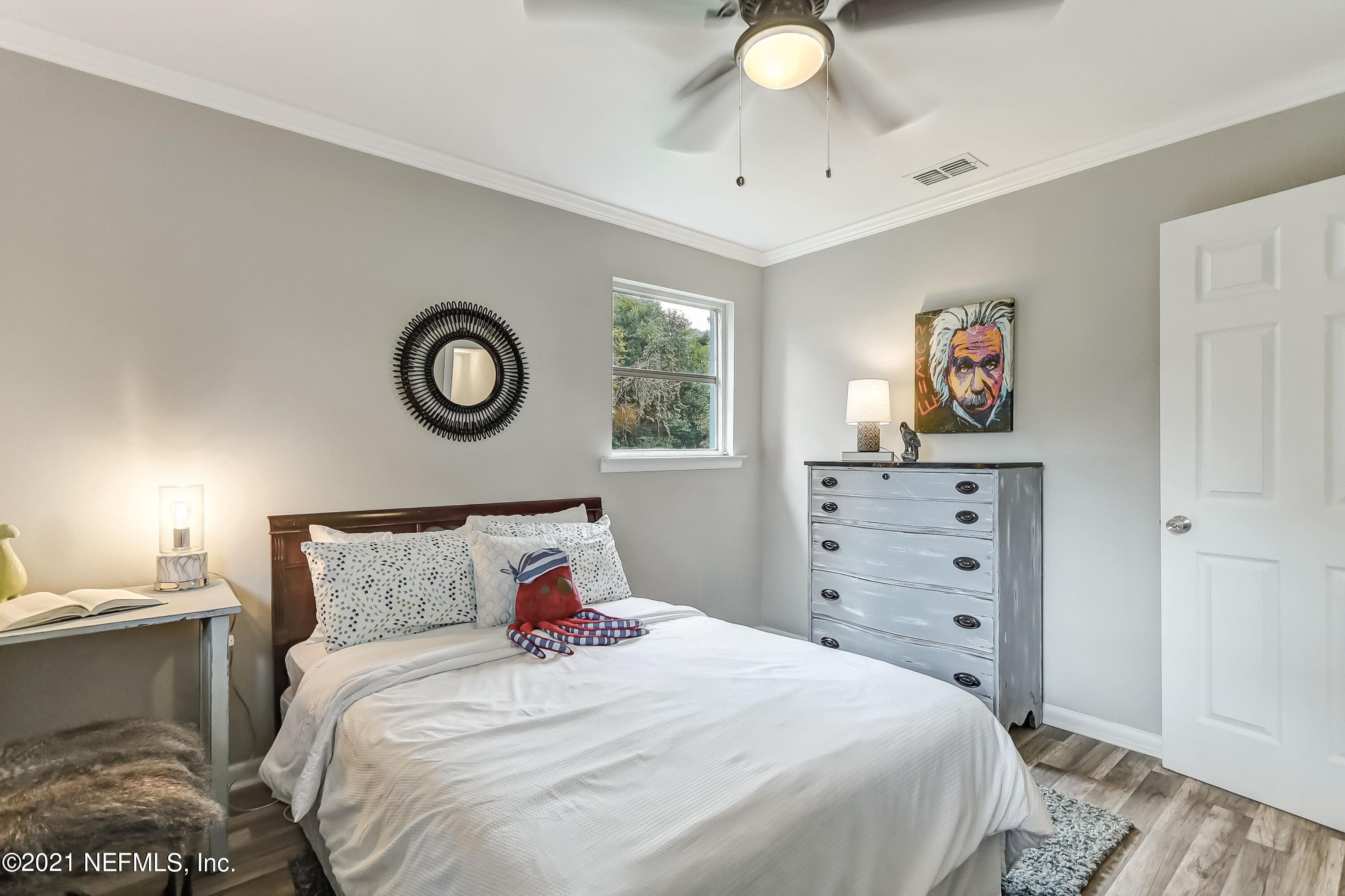 6914 Rollo Road Jacksonville, FL 32205 - Photo 20 of 31 a bedroom with a bed and a chandelier