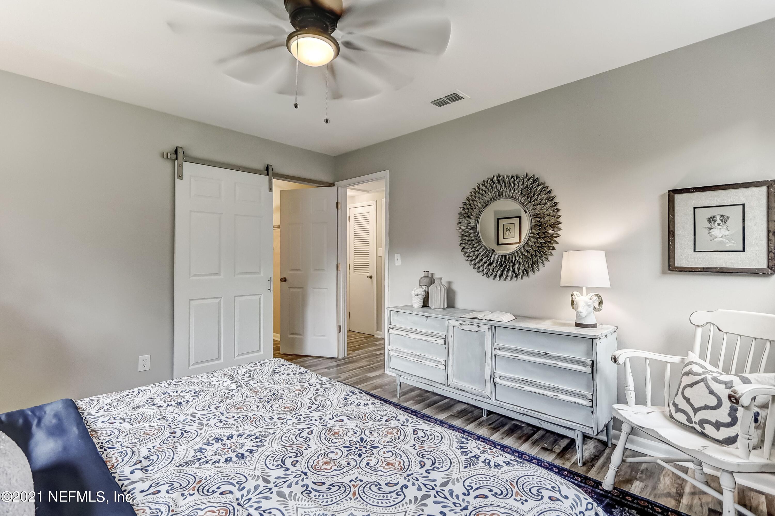 6914 Rollo Road Jacksonville, FL 32205 - Photo 23 of 31 a bedroom with a bed a chandelier and a dresser
