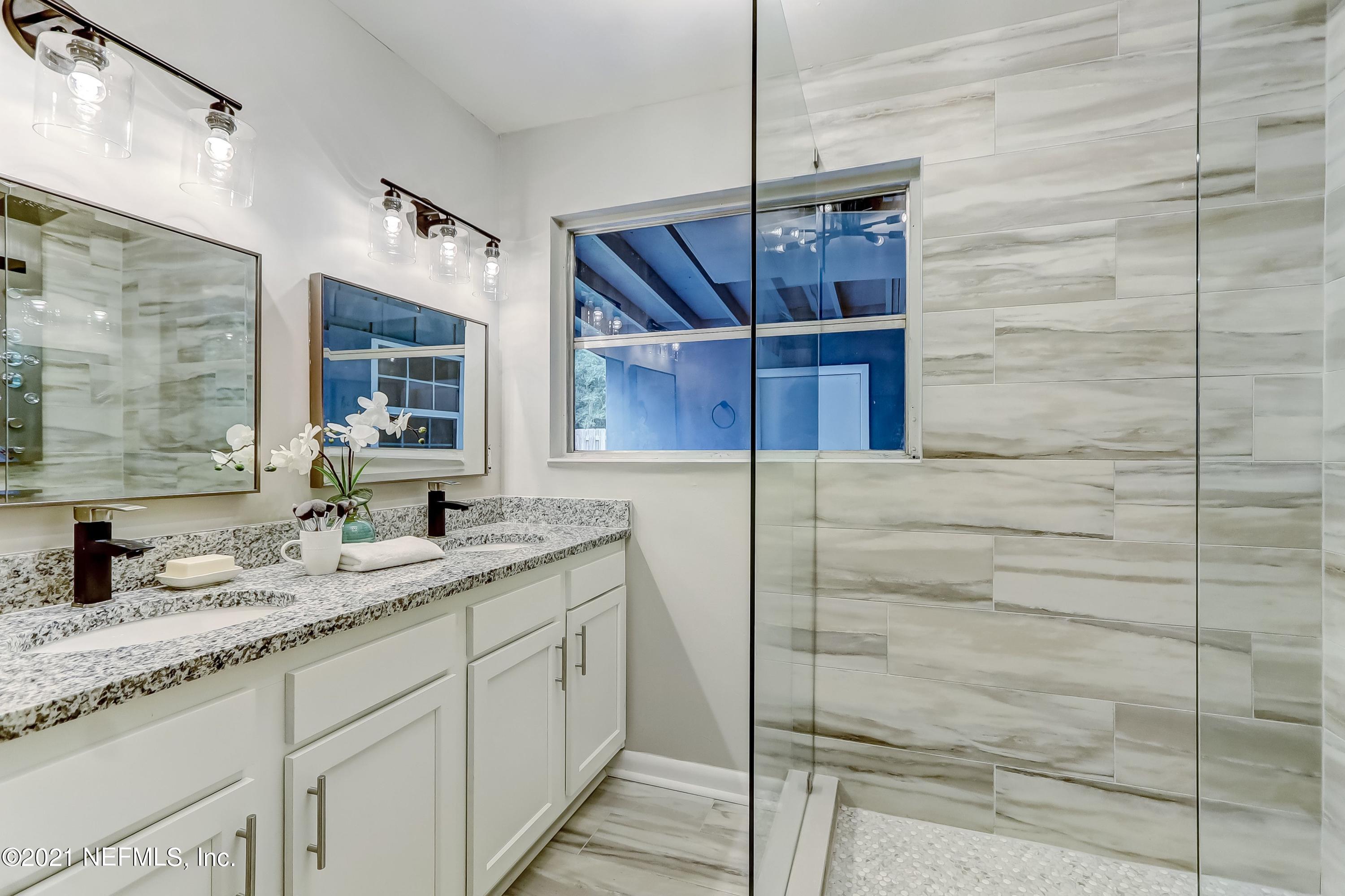 6914 Rollo Road Jacksonville, FL 32205 - Photo 25 of 31 a bathroom with a granite countertop sink a mirror and shower