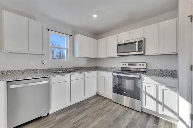 a kitchen with granite countertop white cabinets stainless steel appliances and a sink