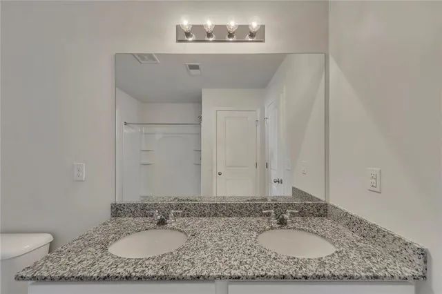 a bathroom with a granite countertop sink a mirror and a toilet