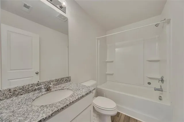a bathroom with a granite countertop sink a toilet and bathtub