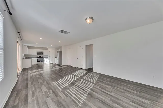 a view of kitchen and empty room with wooden floor