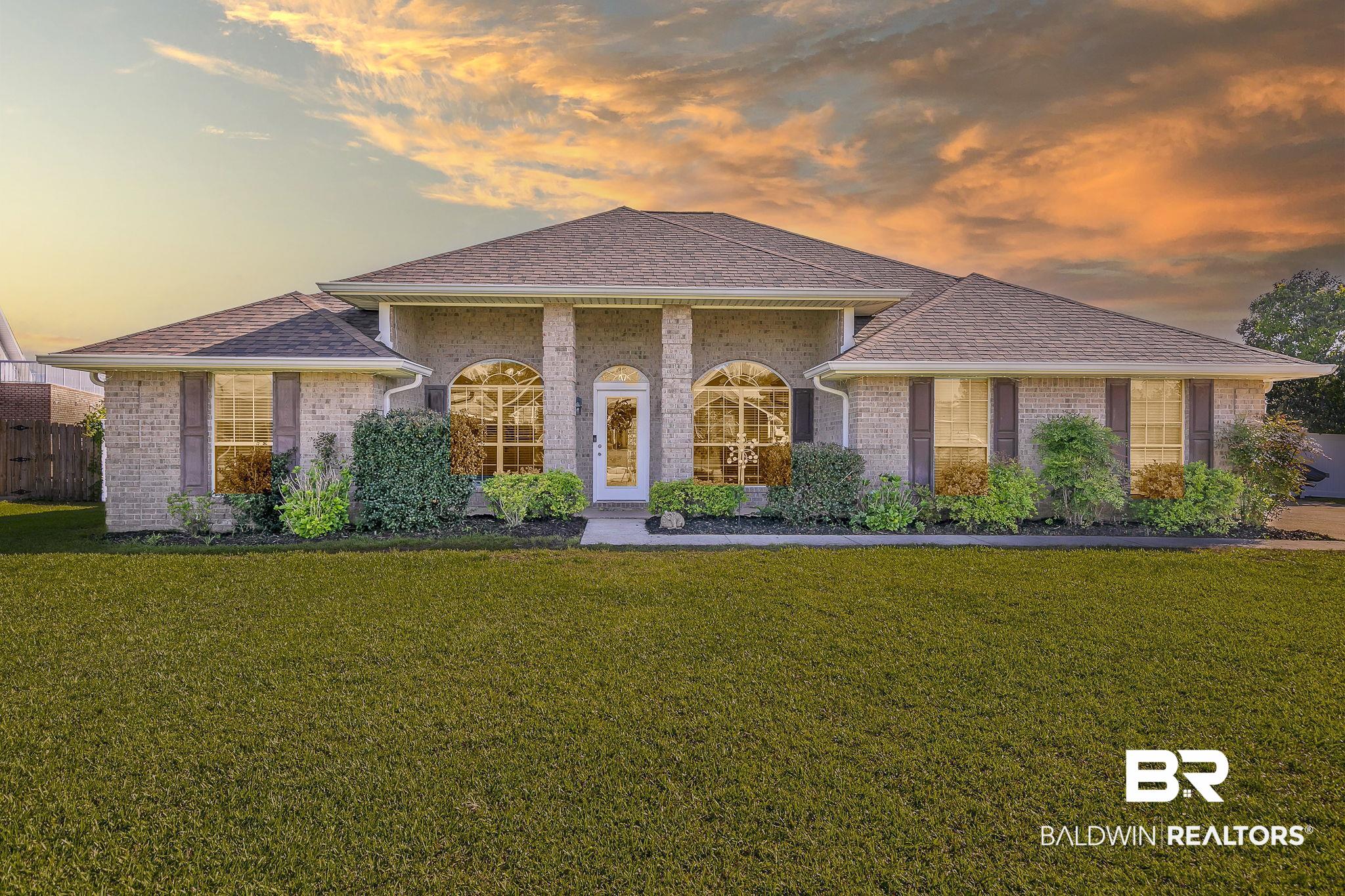 View of front of property with a lawn, a shingled roof, and brick siding