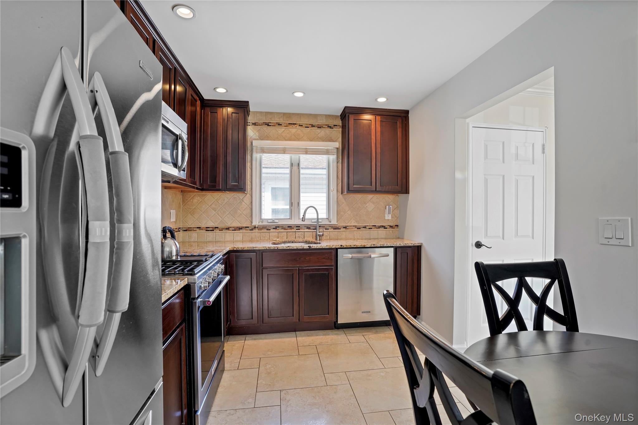 91-03 156th Avenue Queens, NY 11414 - Photo 15 of 50 Kitchen featuring stainless steel appliances, light stone counters, backsplash, dark brown cabinetry, and recessed lighting