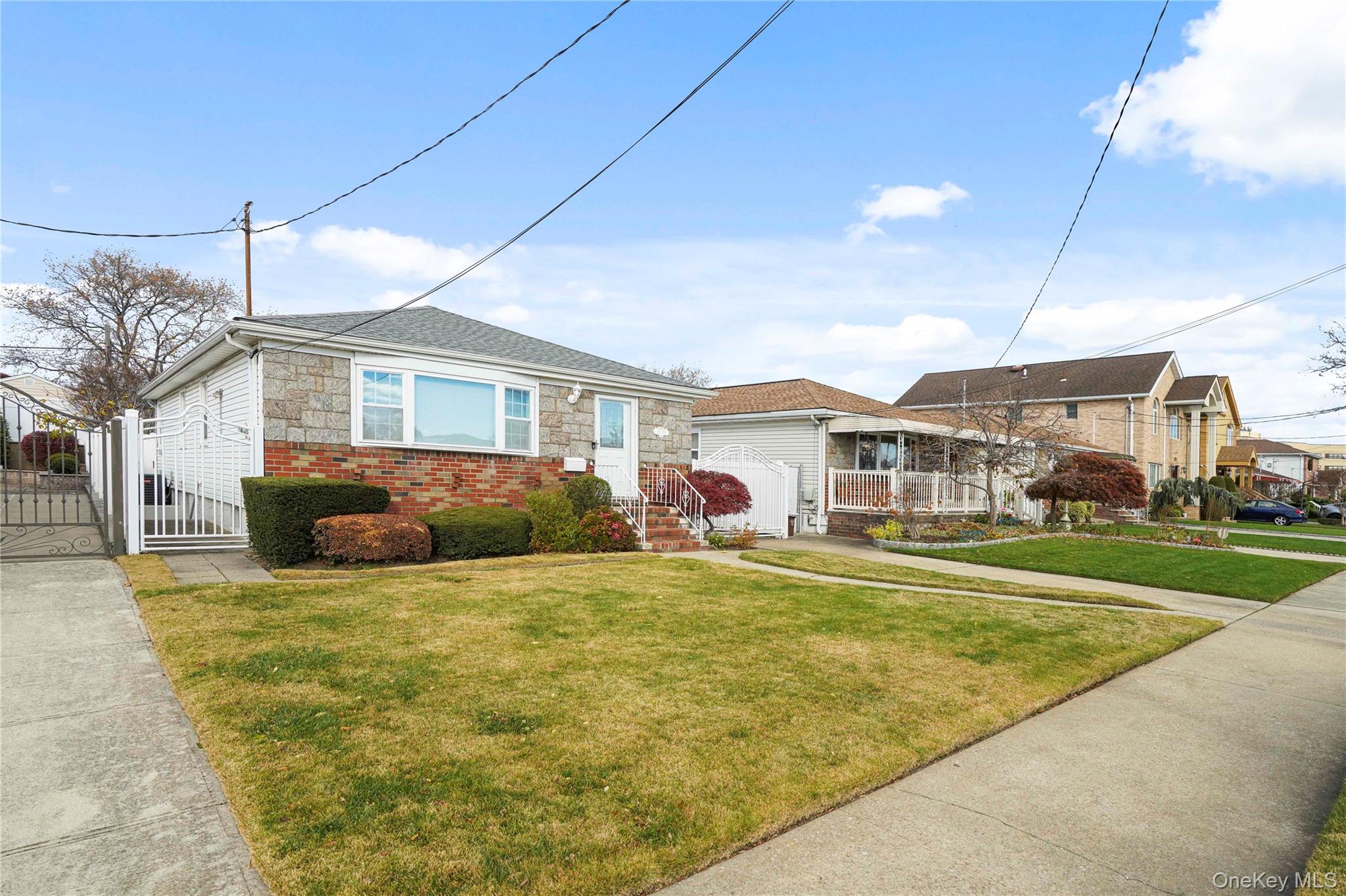 91-03 156th Avenue Queens, NY 11414 - Photo 49 of 50 Bungalow with a gate, stone siding, a front lawn, and brick siding