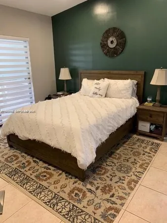 a bed sitting in a bedroom next to a window and a lamp