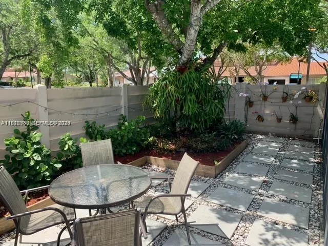 a backyard with table and chairs potted plants and large tree