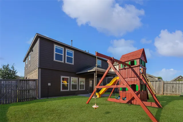 a backyard of a house with wooden fence and a slide