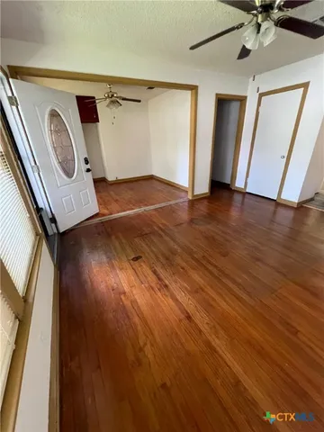 a view of a livingroom with wooden floor and a ceiling fan