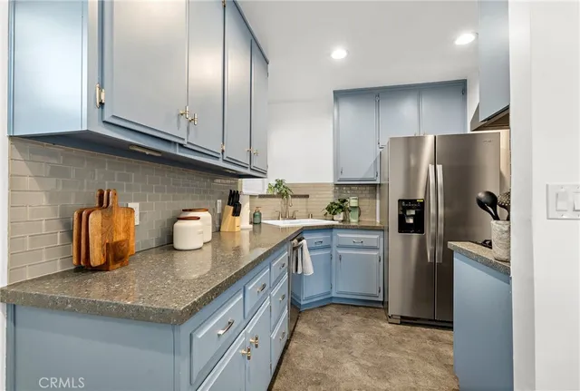 a kitchen with granite countertop stainless steel appliances a sink a refrigerator a stove and cabinets