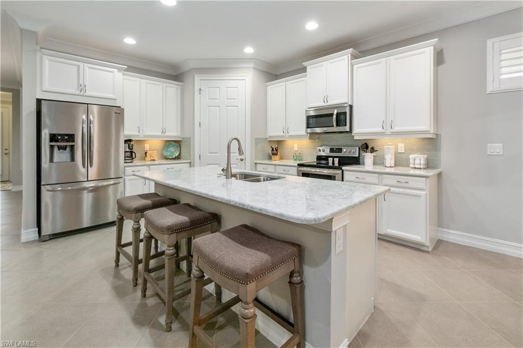14671 Topsail Drive Naples, FL 34114 - Photo 5 of 26 a kitchen with a refrigerator a stove a sink and chairs