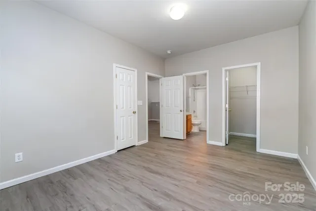 a view of an empty room with wooden floor and closet