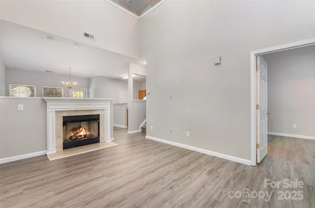 a view of an empty room with wooden floor and fireplace