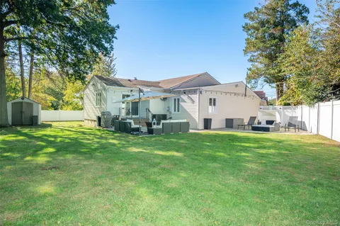a view of a white house in front of a big yard with large trees